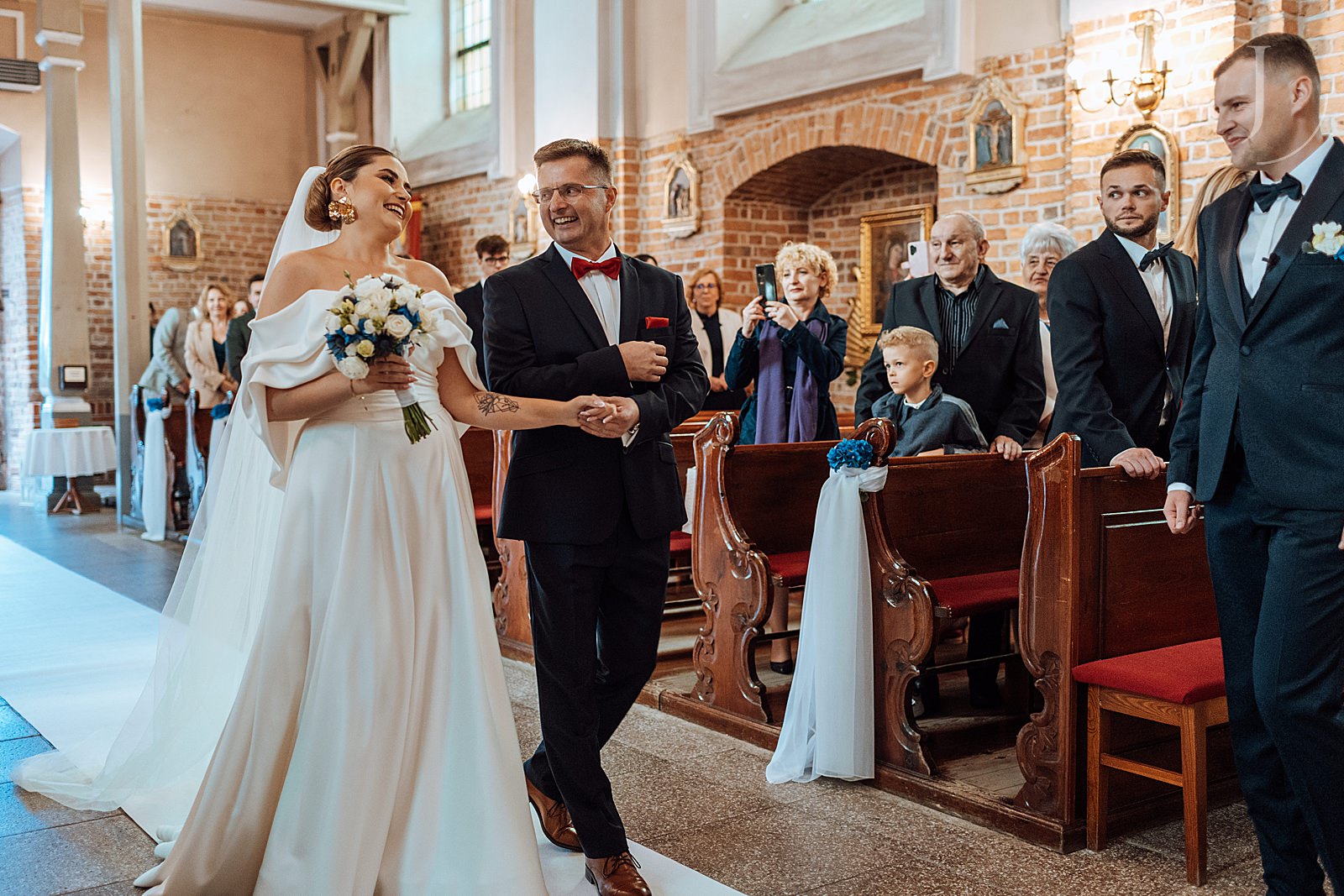 Tata prowadzi Pannę Młodą do ołtarza.