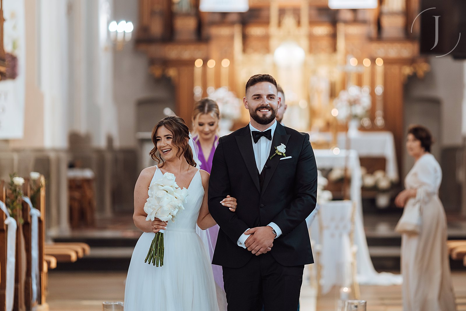 Uśmiechnięta Para Młoda wychodzi z kościoła.